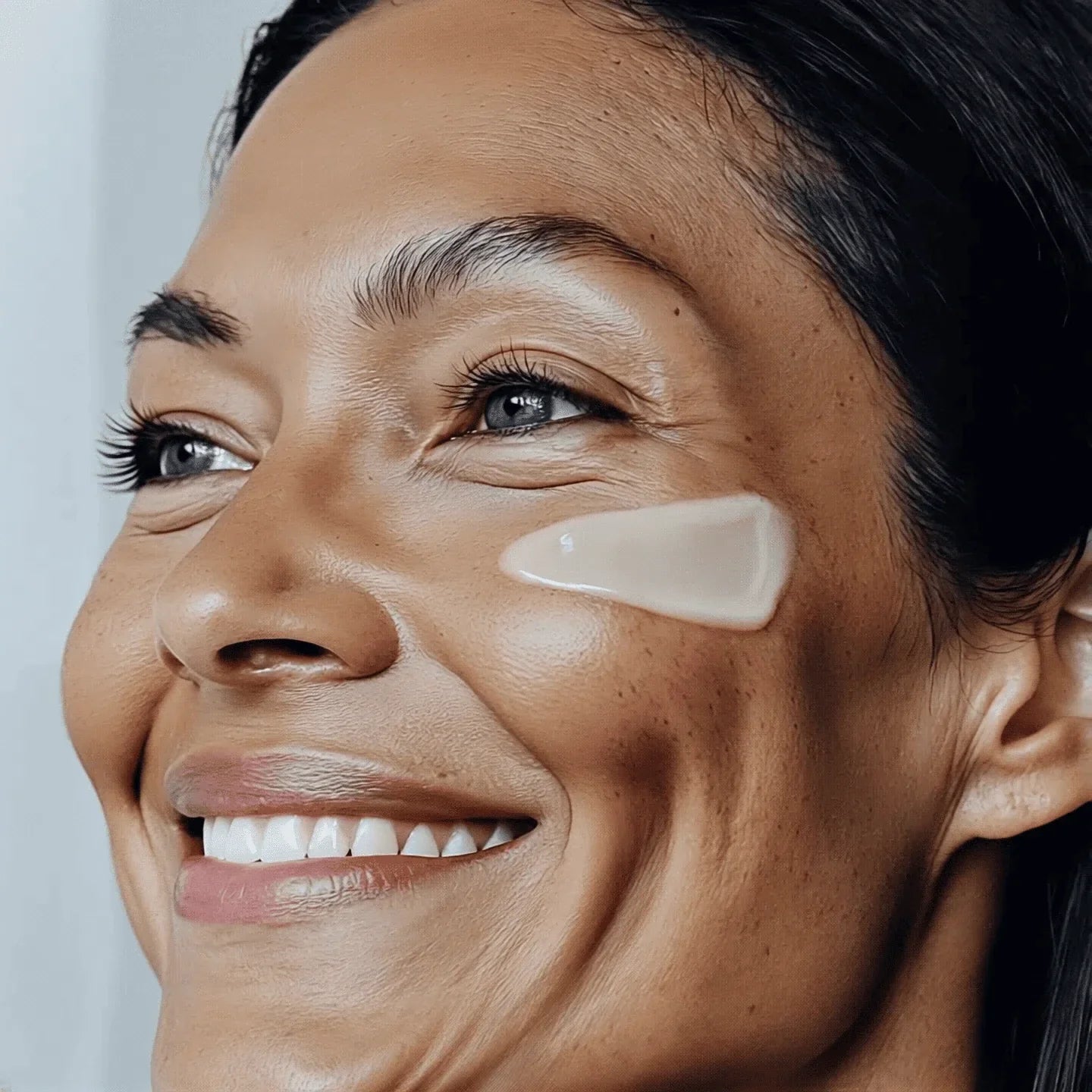 a woman using face cream on her cheek showing a beautiful healthy aging skin
