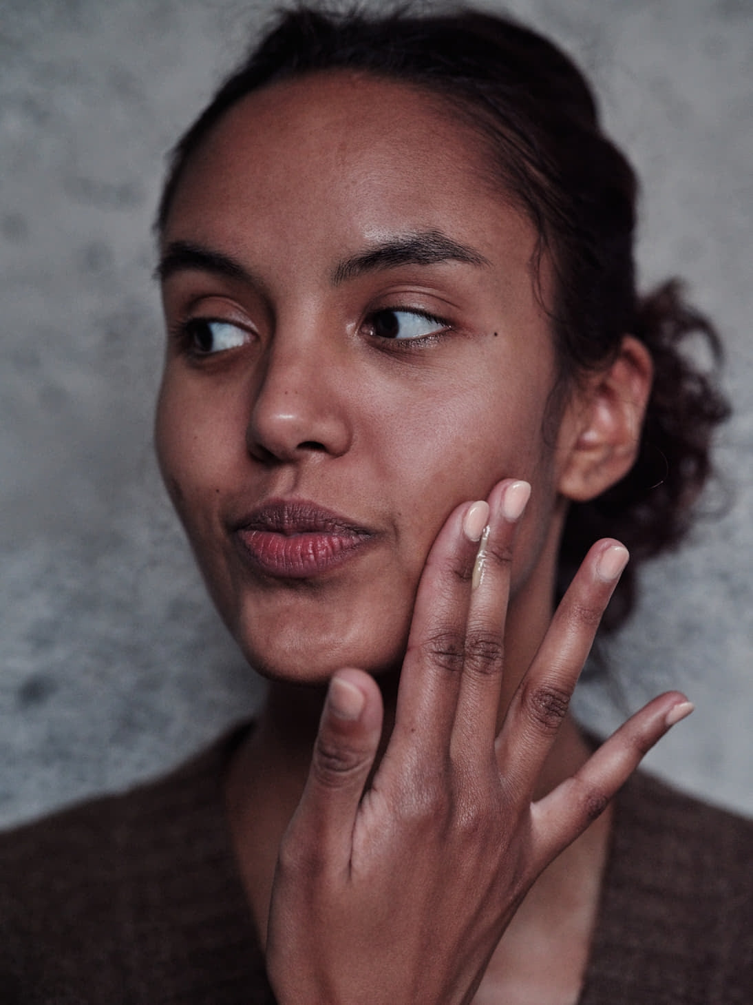 Woman with hand on face against a gray background