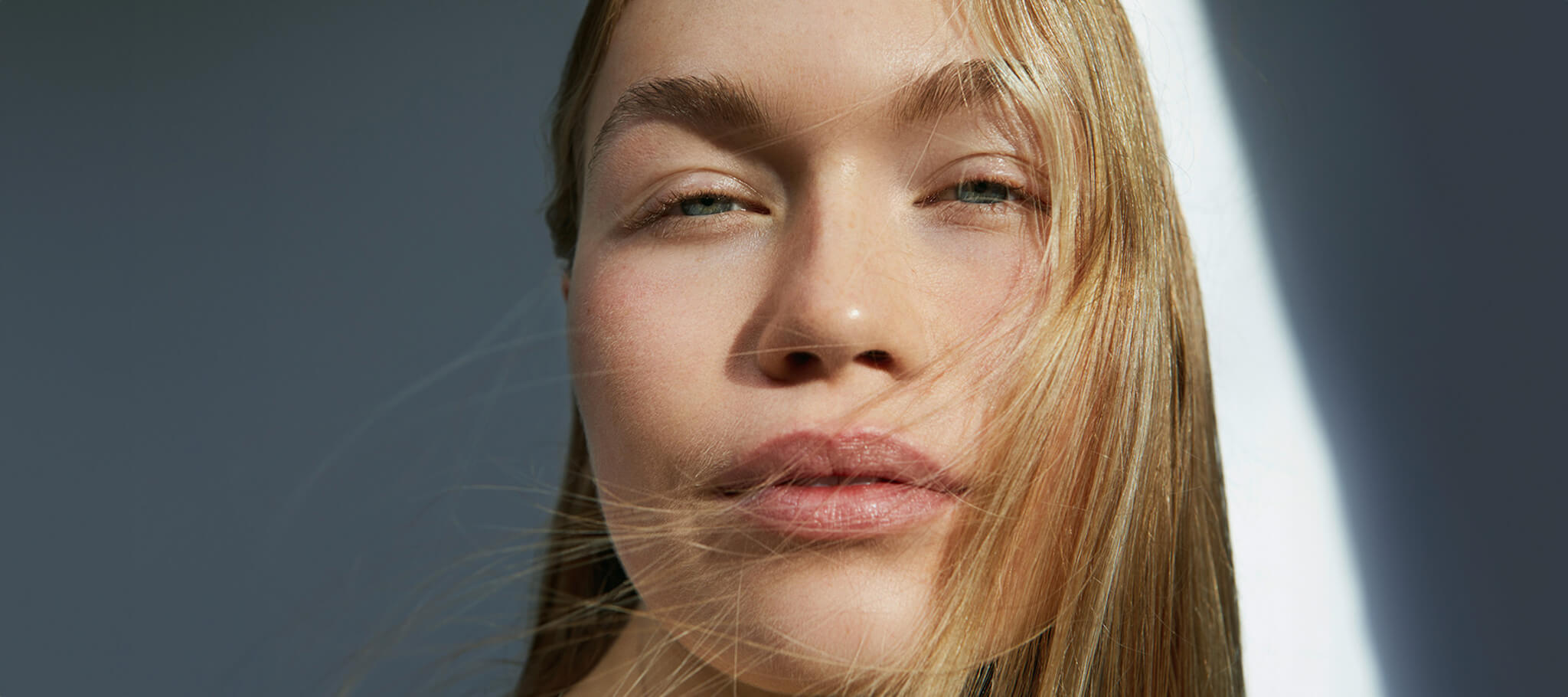 Woman with naturally radiant skin in soft natural light, reflecting JK7®'s philosophy of beauty through balance and holistic wellbeing