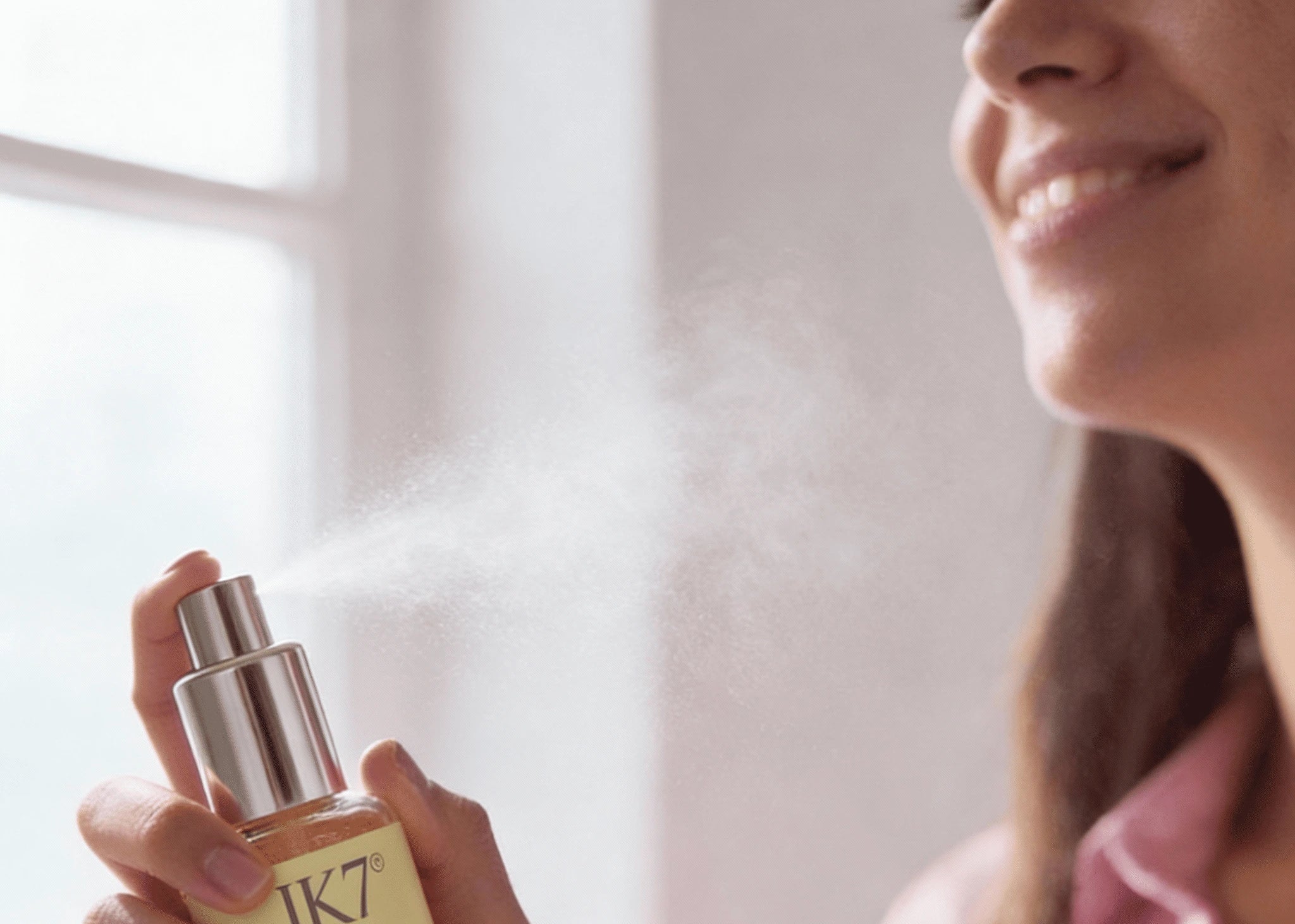 Woman holding a bottle of JK7 skincare product with a blurred background