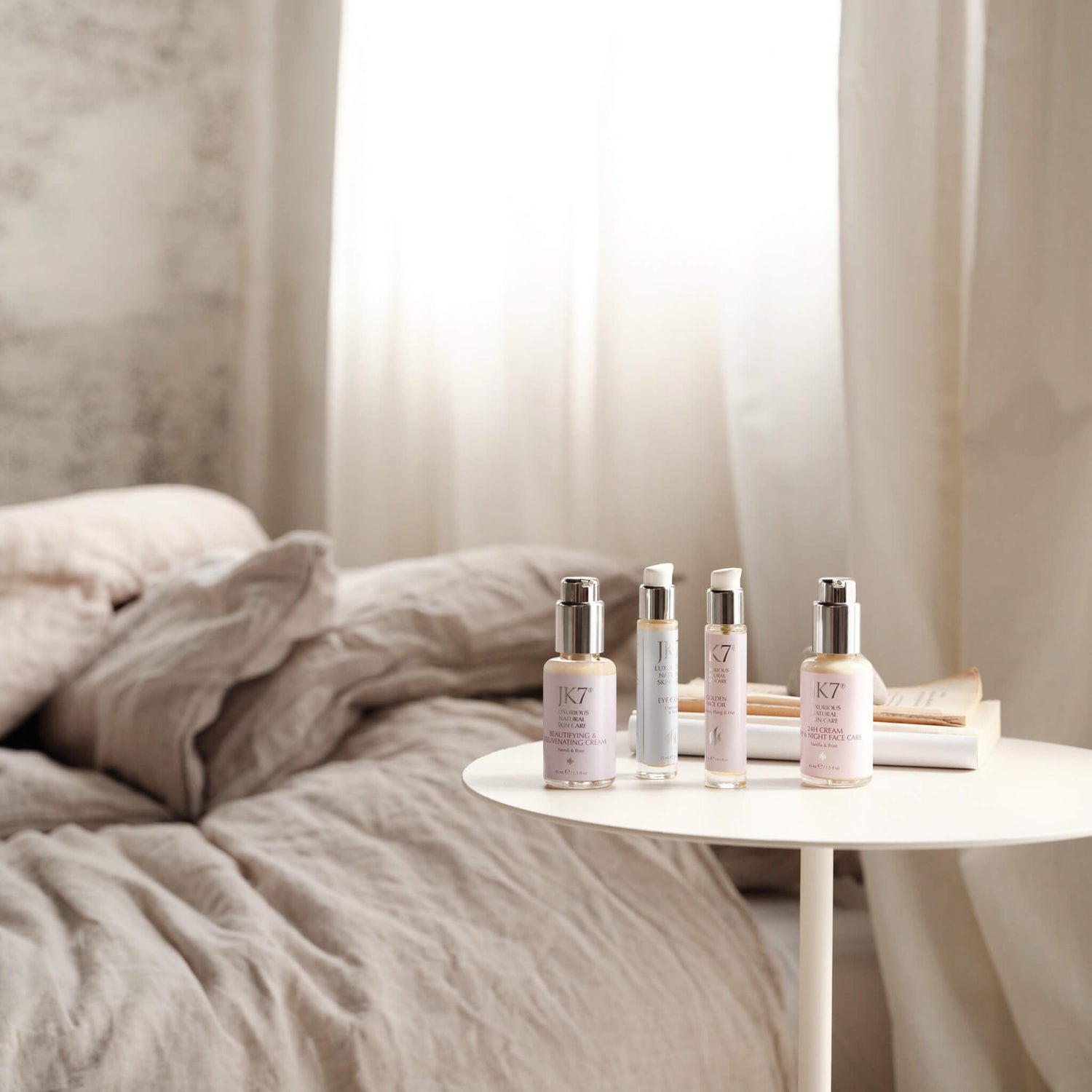 - JK7 skincare products arranged on a bedside table in soft morning light, highlighting a peaceful self-care ritual.