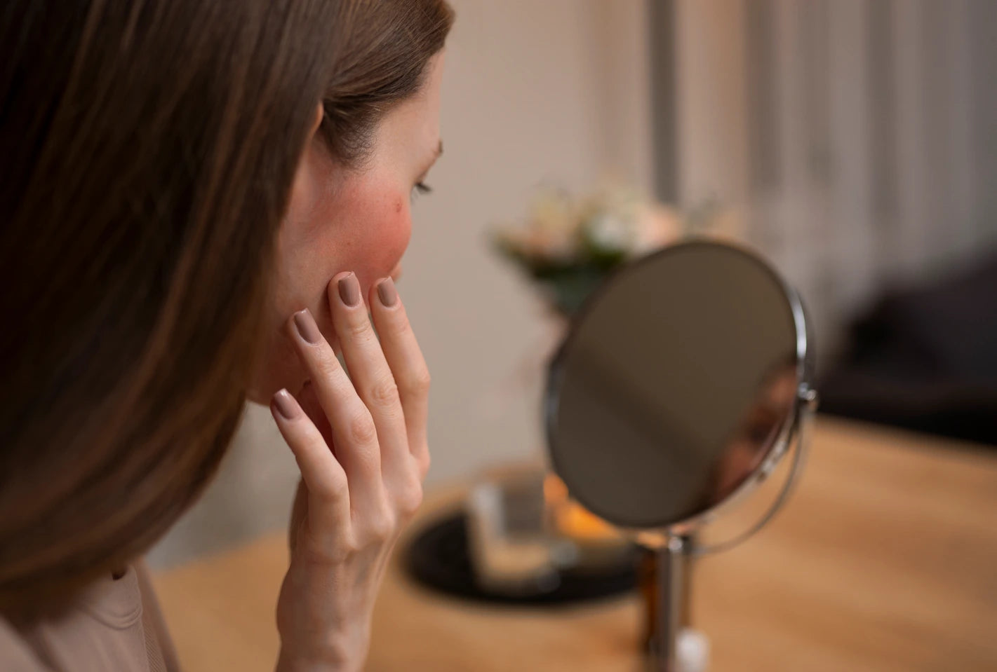 Woman examining her face in a mirror with a blurred background